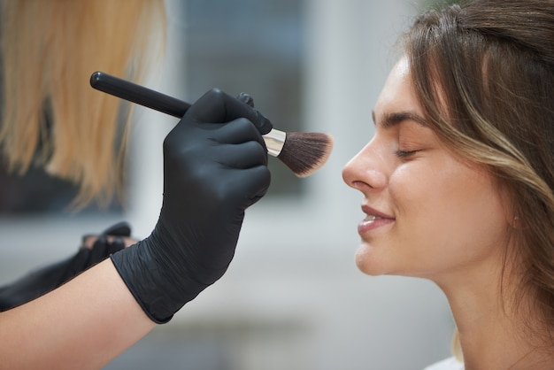 Enfoque selectivo del cliente que consigue maquillaje profesional en salón de belleza