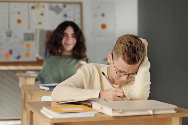 Enfoque selectivo en colegial inteligente y diligente que toma notas en el cuaderno