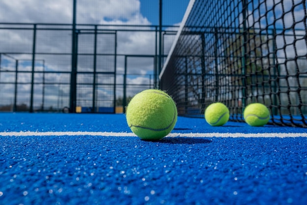 enfoque selectivo, cuatro pelotas de pádel en una cancha de pádel azul cerca de la red, concepto de deportes de raqueta