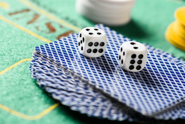 Foto enfoque selectivo de los dados en las cartas de juego en la baraja con fichas y mesa de póquer verde en el fondo