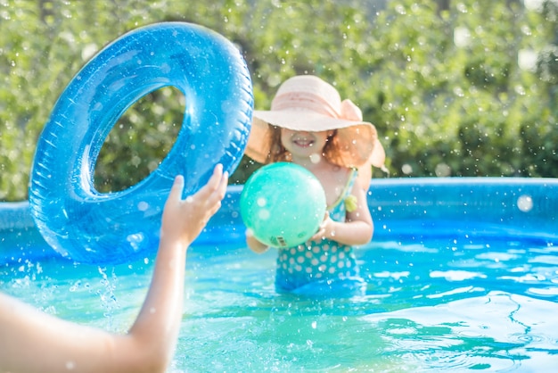 Enfoque selectivo, desenfoque devokus. Los niños juegan con una pelota en la piscina en verano. niña y niño al aire libre