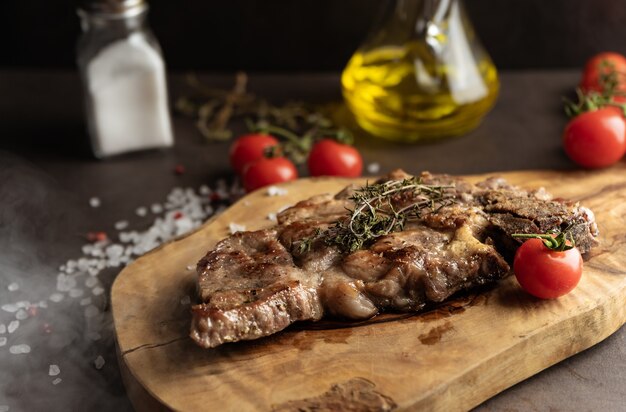 Foto enfoque selectivo. filete de cerdo marmolado frito en estilo rústico. sobre una tabla de madera, con sal gruesa y especias. bajo perfil, primer plano