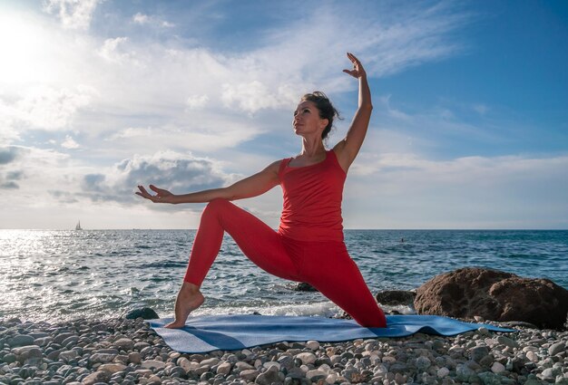 Enfoque selectivo joven hermosa mujer caucásica en un traje rojo practicando yoga fitness y estiramientos