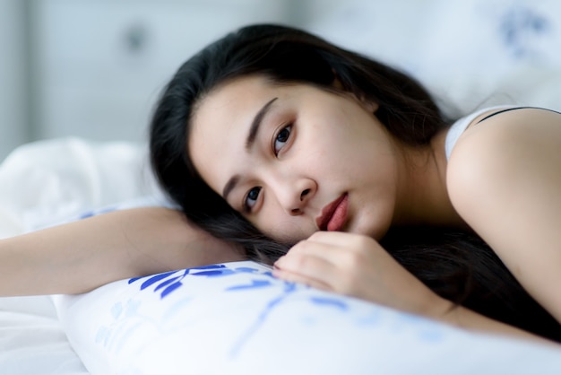 El enfoque selectivo en la joven mujer asiática yacía en una cama después de despertarse por la mañana.