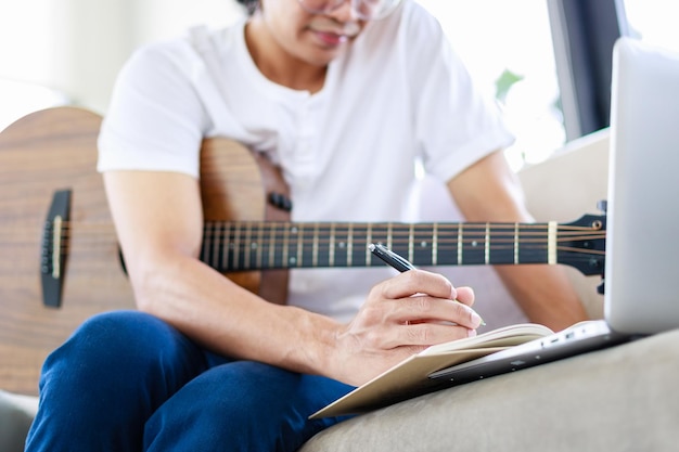 Enfoque selectivo de la mano del músico componiendo música con guitarra acústica en la sala de estar