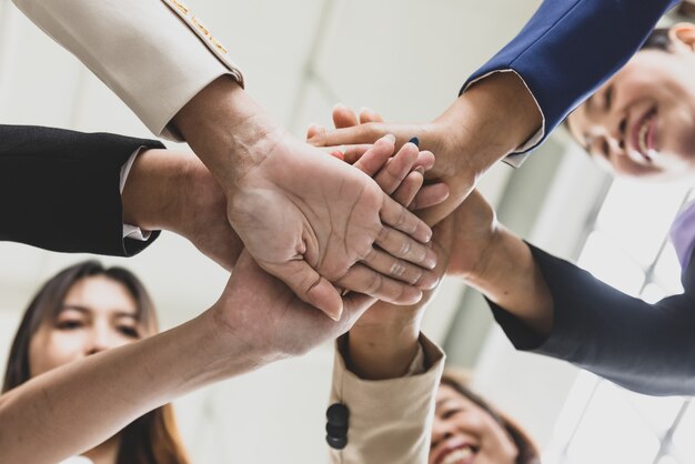 Enfoque selectivo en las manos de varias mujeres de negocios en trajes formales juntos durante una reunión de negocios con caras borrosas en el fondo. Concepto de reunión de negocios.