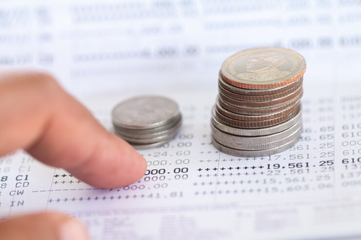 Foto enfoque selectivo de las monedas de tailandia apiladas sobre la página del extracto de la cuenta bancaria sobre fondo blanco, recaudando dinero por concepto de inversión con espacio de copia