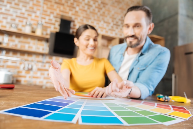 Enfoque selectivo de la muestra de color que yace en la superficie mientras alegre feliz pareja feliz apuntando y riendo