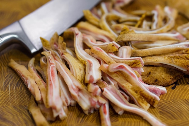 Enfoque selectivo en la oreja de cerdo en rodajas crudas y el cuchillo principal en el escritorio de madera Menú de cocina asiática