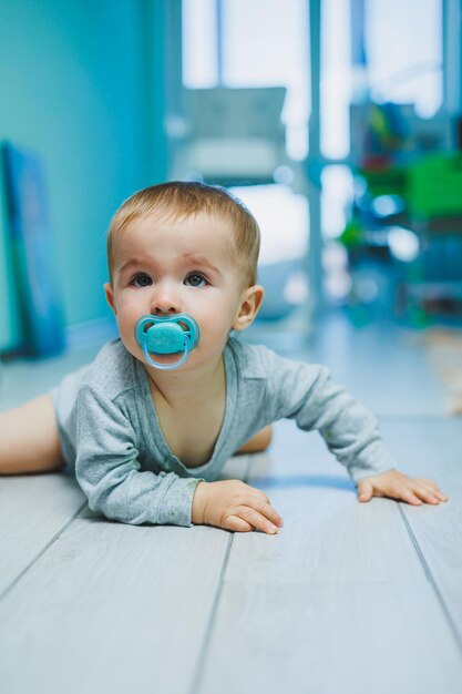 Enfoque selectivo de pañales para bebés con un niño pequeño en el fondo sentado en el baño de los niños en casa en el piso durante el día completo con chupete de pezón en la boca espacio de copia de vista frontal