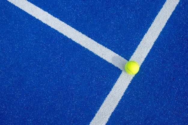 Foto enfoque selectivo de una pelota en la línea blanca de una cancha de pádel azul