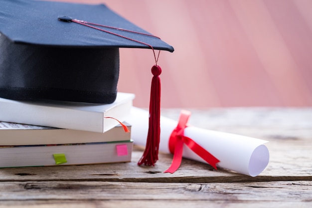 Enfoque selectivo de primer plano de una gorra de graduación o birrete y certificado de título de diploma puesto sobre la mesa