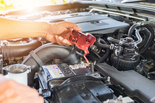 Enfoque selectivo, técnico hombre mano comprobando la batería del automóvil en el sistema del motor del automóvil