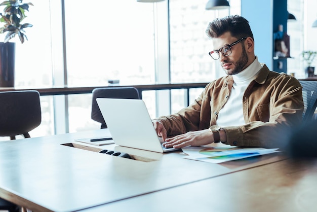 Enfoque selectivo del trabajador de TI en anteojos usando una computadora portátil en el espacio de coworking