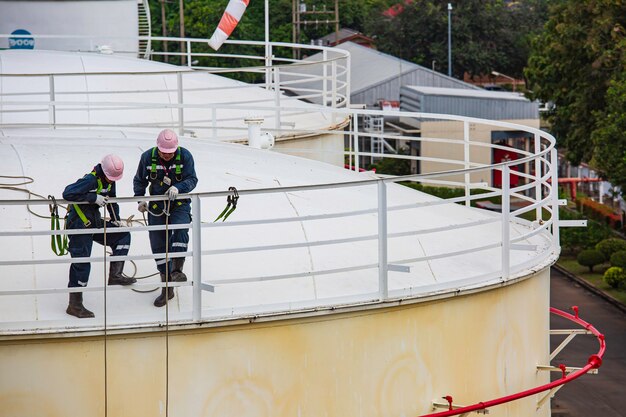 Enfoque trabajador masculino acceso por cuerda inspección de seguridad de altura del tanque de aceite y gas de almacenamiento de espesor