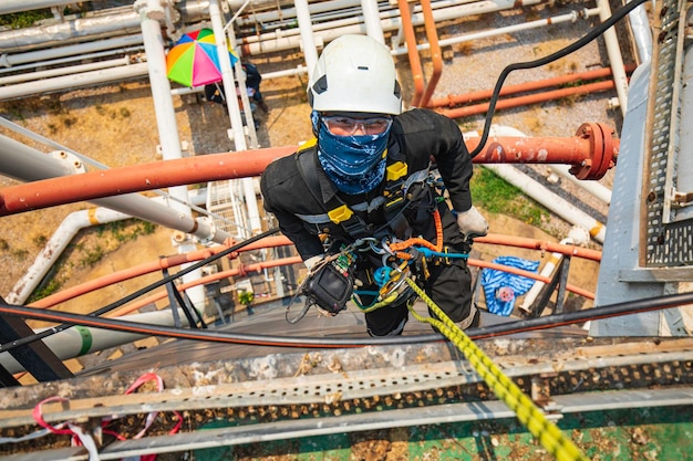 Enfoque vista superior trabajador masculino abajo altura techo del tanque acceso por cuerda inspección de seguridad del espesor del tanque de almacenamiento de petróleo crudo