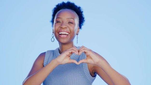 Enfrente as mãos do coração e a mulher negra com feedback de apoio e bem-estar em um fundo azul Retrato pessoa africana e modelo com símbolo de amor, respeito e cuidado com feedback de revisão e esperança