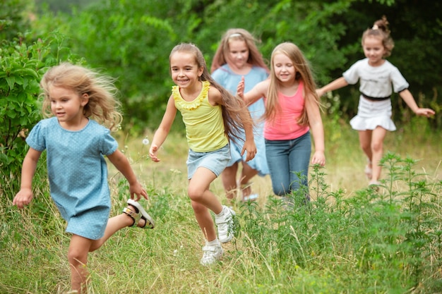 Engel. Kinder, Kinder, die auf grünem Wald laufen Fröhliche und fröhliche Jungen und Mädchen spielen, lachen, laufen durch die grüne blühende Wiese. Kindheit und Sommer, Konzept der aufrichtigen Emotionen.