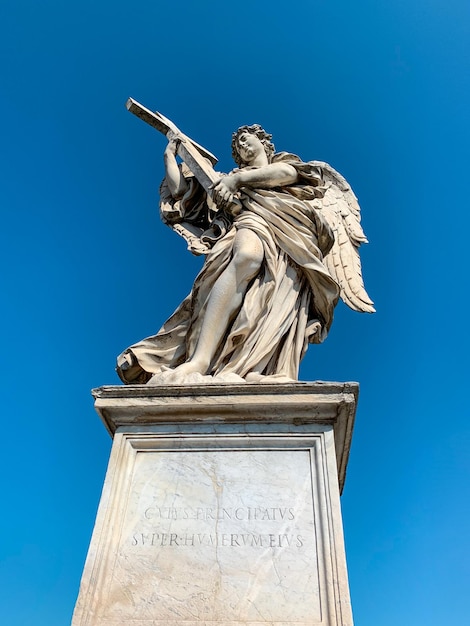 Engel Steinskulptur mit römischen Inschriften über hellem Himmelshintergrund. Rom. Italien.