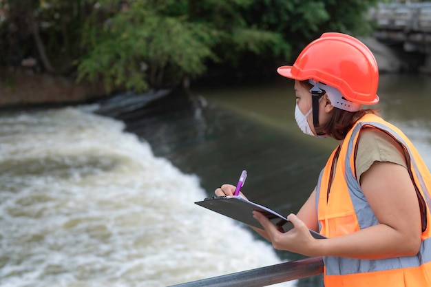 Foto engenharia feminina asiática trabalhando xa na estação de tratamento de esgoto biólogo marinho analisando resultados de testes de águaconceito do dia mundial do meio ambiente