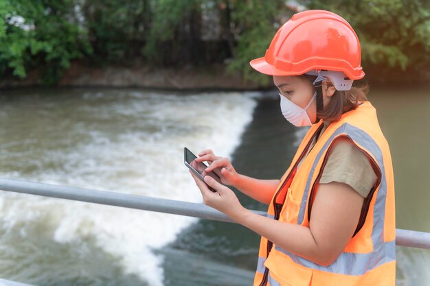 Engenharia feminina asiática trabalhando xA na estação de tratamento de esgoto Biólogo marinho analisando resultados de testes de águaConceito do dia mundial do meio ambiente