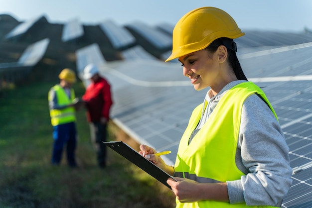 Engenheira caucasiana em capacete olhando os documentos e lendo conselhos da governança trabalhando no canteiro de obras da usina solar