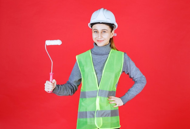 Engenheira com capacete branco segurando um rolo aparador.