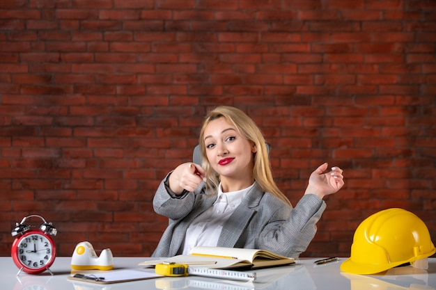 Engenheira de frente, sentada atrás de seu local de trabalho