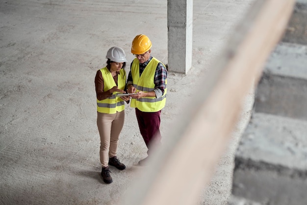 Engenheiras caucasianas discutindo com um homem sênior no canteiro de obras