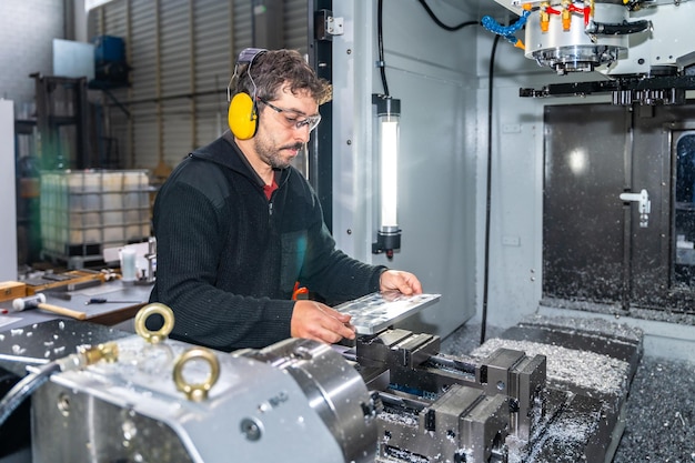 Engenheiro a trabalhar com uma máquina de fresagem CNC usando equipamento de segurança