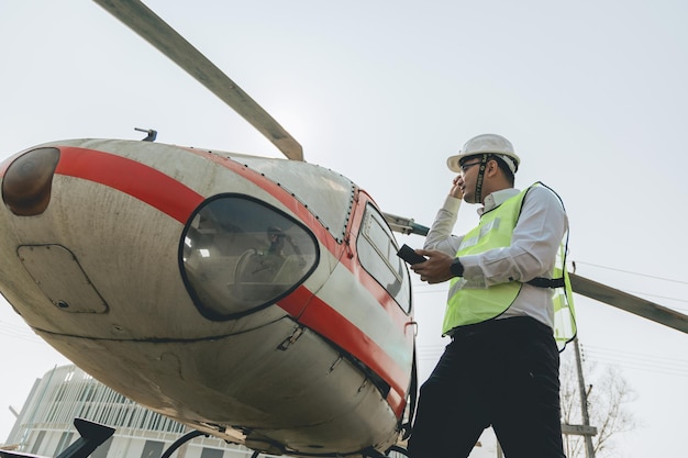 Engenheiro aeronáutico asiático trabalhando em helicóptero no hangar olhando para tablet digital