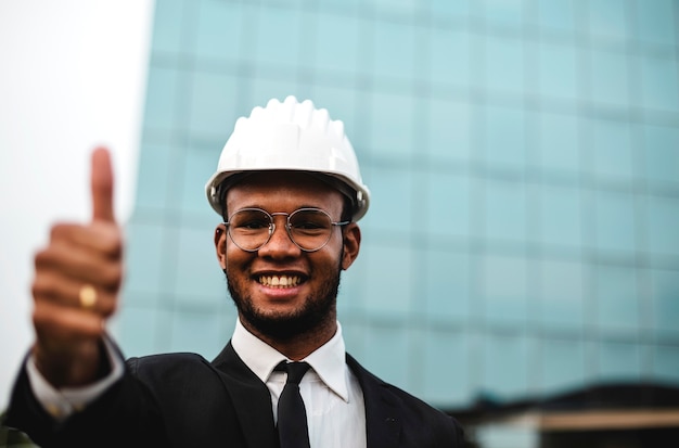 Foto engenheiro africano em frente a um arranha-céu funciona bem como um sinal de positividade