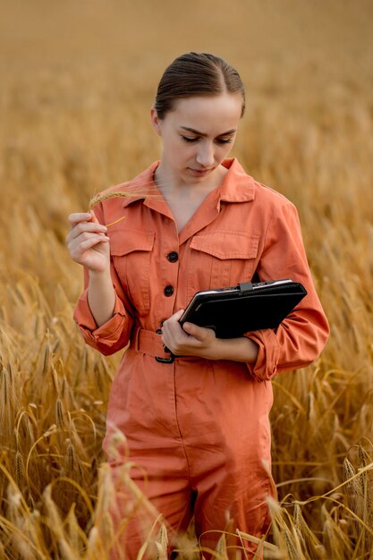 Engenheiro agrônomo de mulher caucasiana com computador tablet no campo de trigo, verificando a qualidade e o crescimento das safras para a agricultura. agricultura e conceito de colheita.