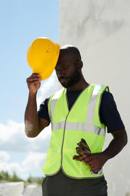 Engenheiro americano africano careca de uniforme colocando capacete de segurança na cabeça