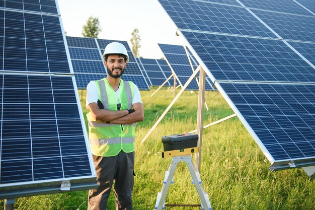 Engenheiro árabe de pé no campo com fileiras de painéis solares
