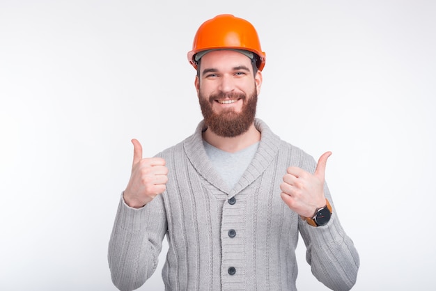 Engenheiro, arquiteto ou construtor homem usando um capacete mostrando como gesto, ambos os polegares para cima.