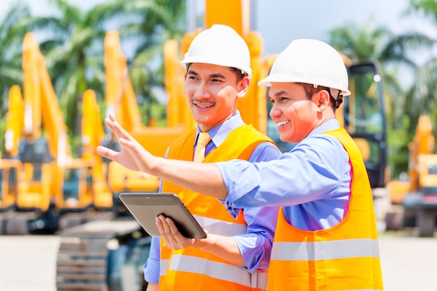 Engenheiro asiático, discutindo planos no canteiro de obras