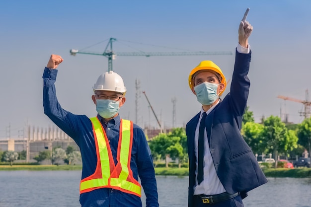 Engenheiro asiático e capataz com touch pad discutem o plano de trabalho para o canteiro de obras ao ar livre