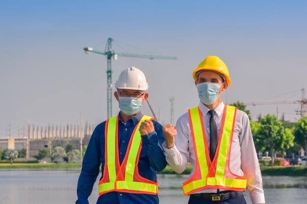 Engenheiro asiático e capataz com touch pad discutem o plano de trabalho para o canteiro de obras ao ar livre