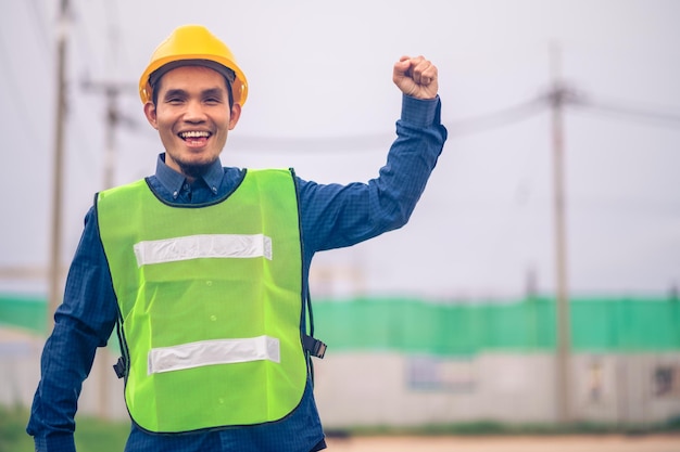 Engenheiro asiático em pé ao ar livre na construção do local postando confiante Engenheiro de construção feliz sucesso no trabalho com planejamento alvo