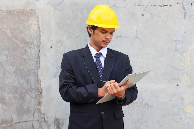 Engenheiro asiático masculino com capacete escrevendo na área de transferência engenheiro civil sério trabalhando com documento