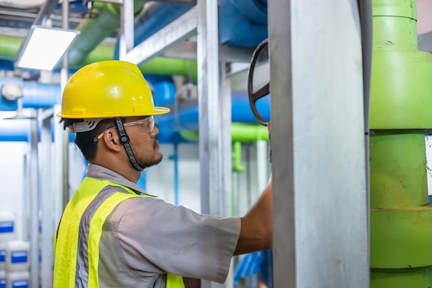 Engenheiro asiático usando óculos trabalhando na manutenção da sala da caldeira verificando dados técnicos do equipamento do sistema de aquecimentoTailândia