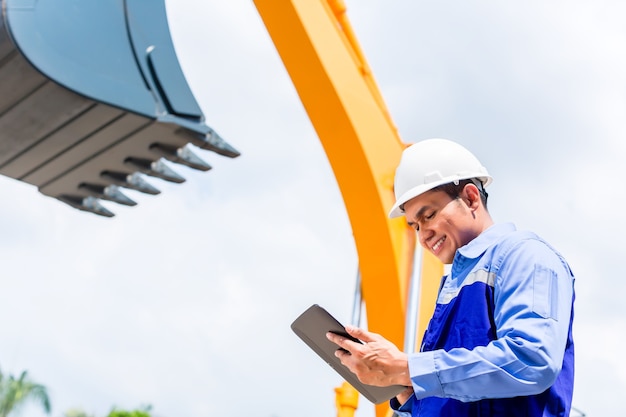 Engenheiro asiático verificando planos no canteiro de obras