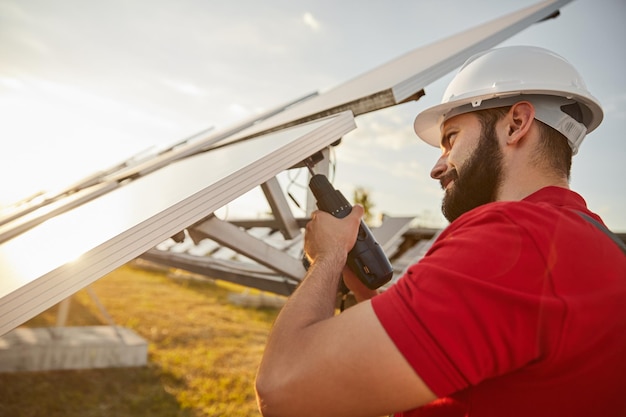 Engenheiro barbudo em capacete parafusando painel solar em campo