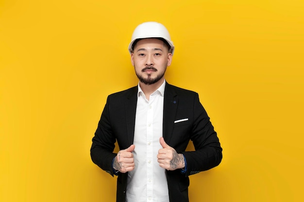 Engenheiro civil asiático em terno em fundo isolado amarelo homem coreano em chapéu duro