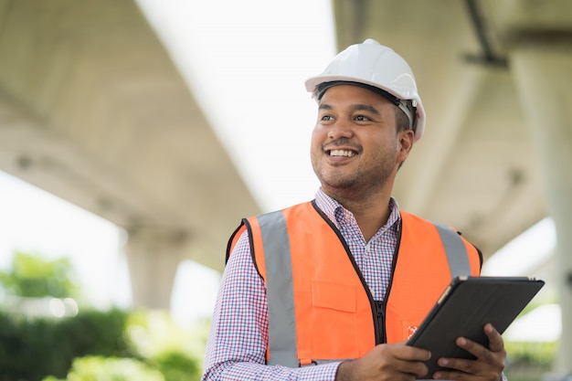 Foto engenheiro civil asiático opera com tablet para controlar o trabalho na construção