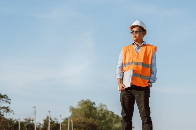 Engenheiro civil no canteiro de obras usando o computador laptop, verificando o trabalho. Gestão no canteiro de obras.