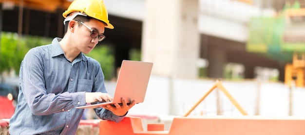 Foto engenheiro civil profissional masculino asiático inteligente segura a verificação da construção do site do laptop com infraestrutura e fundo de construção