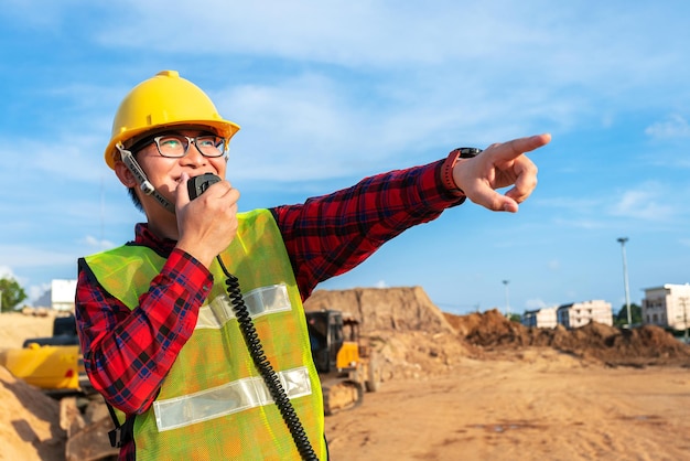 engenheiro civil técnico asiático conversa com equipe por walkie talkie sobre planta no canteiro de obras