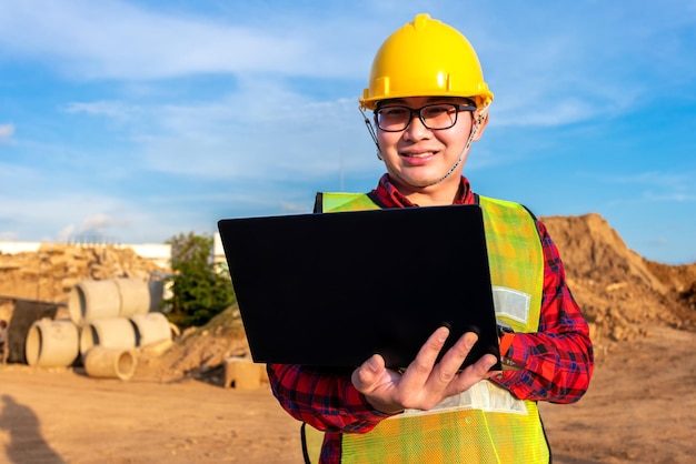 Engenheiro civil técnico asiático usa tablet com tecnologia de caneta inteligente na construção do local de transporte para inspecionar o trabalho de engenharia de planta on-line com a equipe na hora do pôr do sol